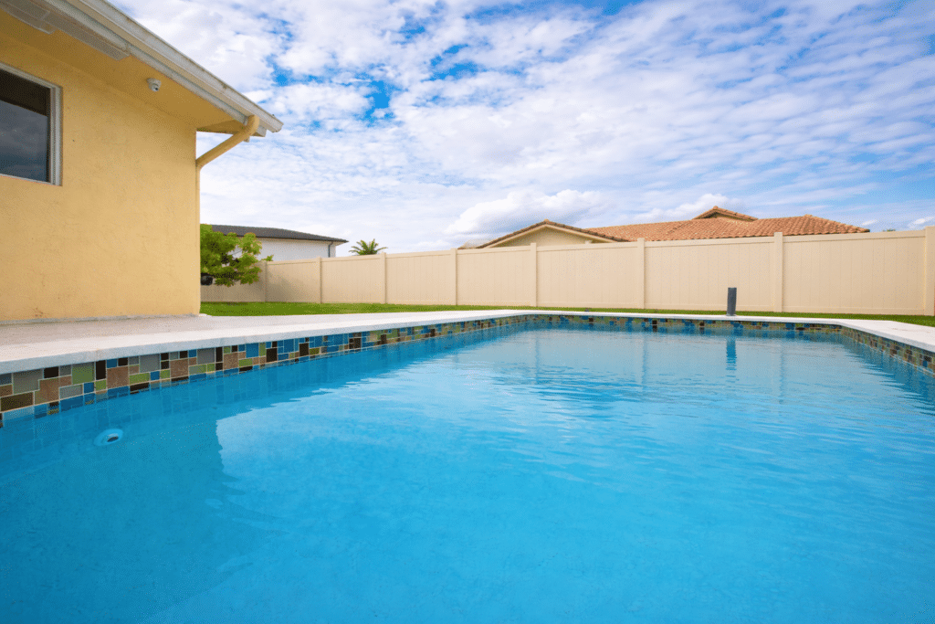 Backyard swimming pool with concrete deck and vinyl privacy fence
