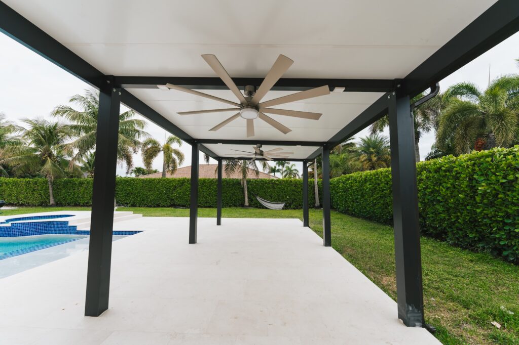 Black aluminum pergola with a ceiling fan shading a pool deck