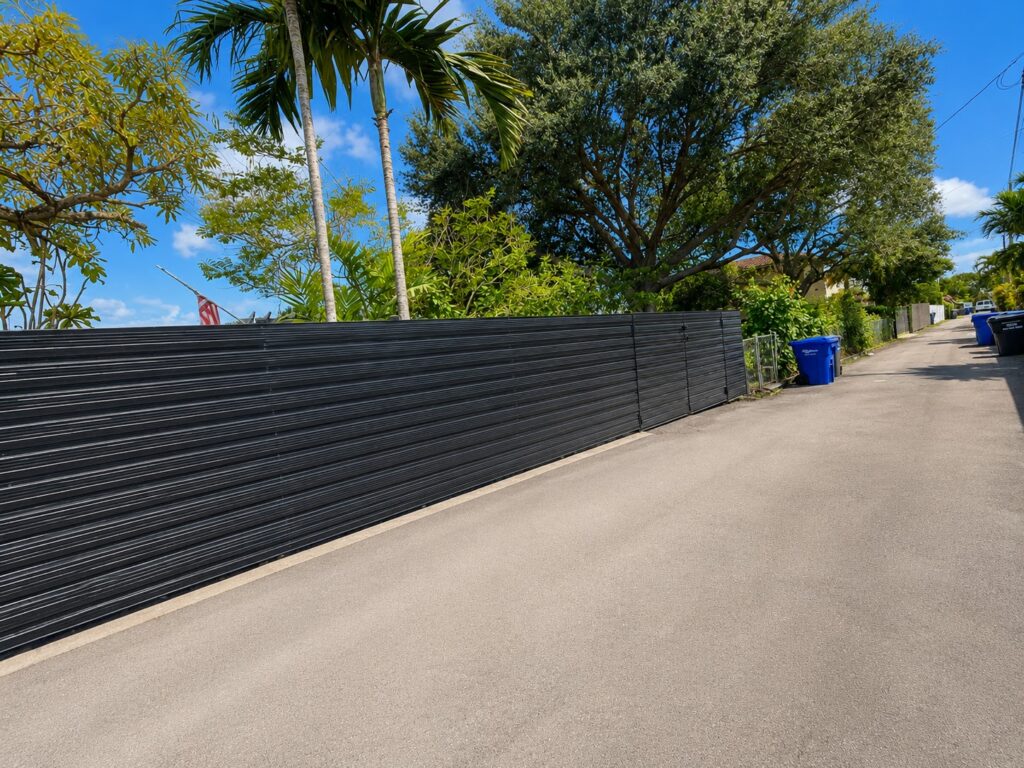 Black horizontal aluminum privacy fence along a residential driveway in South Florida