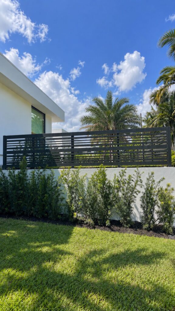 Horizontal aluminum fence on a low wall with landscaping, installed by Canet Group