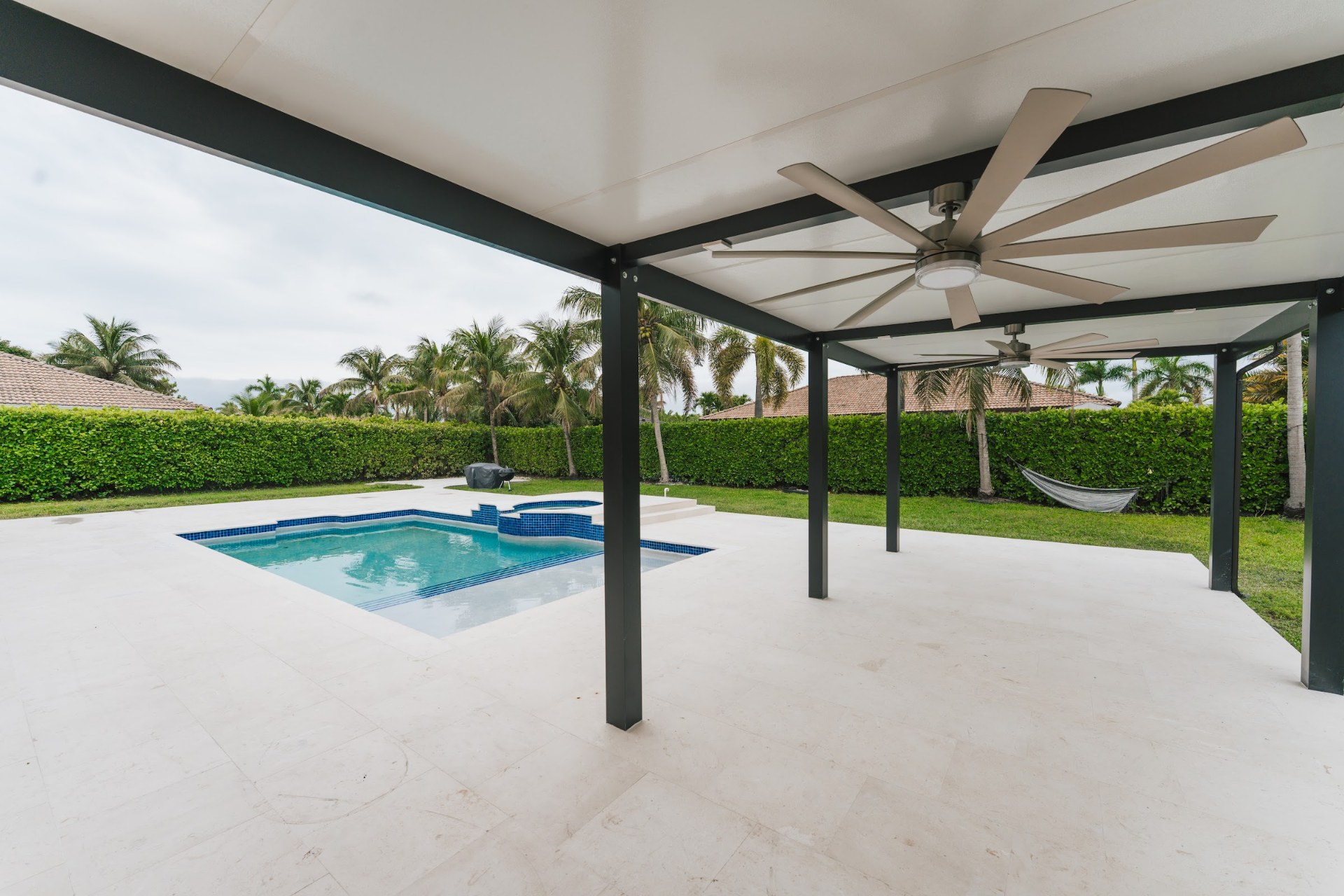 Modern aluminum pergola with a ceiling fan over a pool deck, built by Canet Group