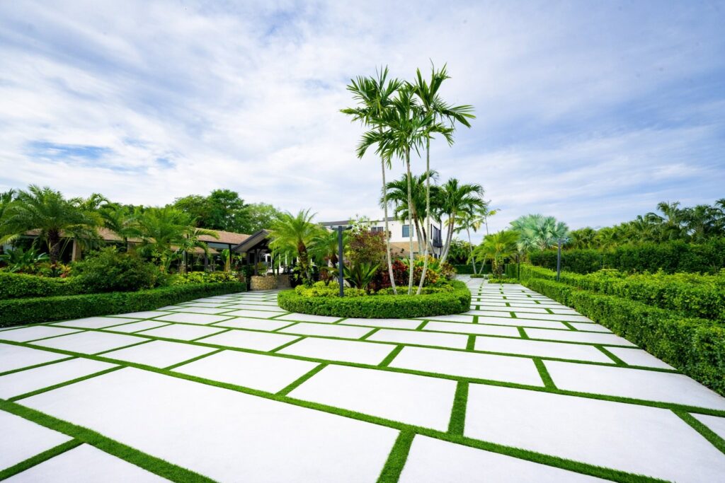 Concrete pavers with turf joints around a palm garden, by Canet Group