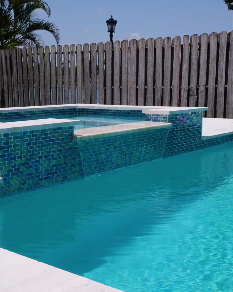Glass tile spa spilling over into a new pool