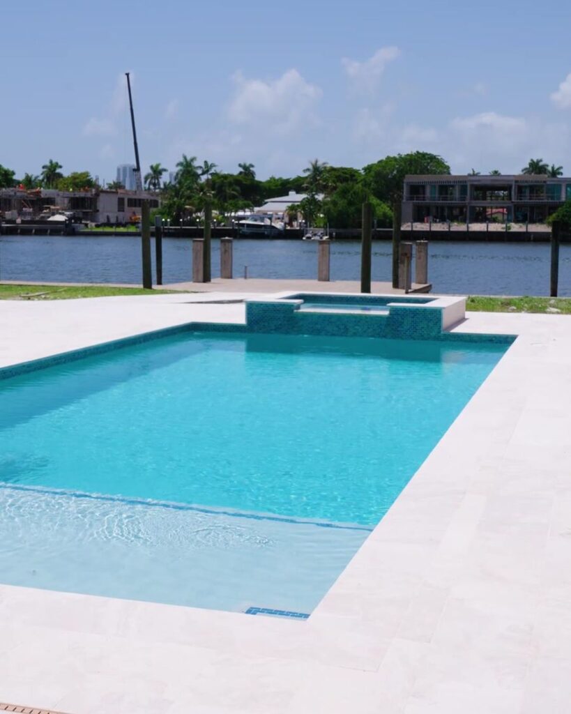 New waterfront pool with a raised spa and travertine deck