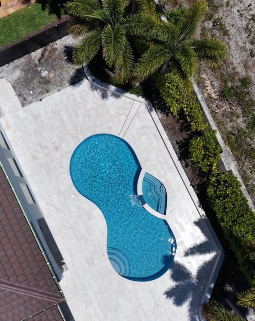 Aerial view of a curved freeform pool with an attached spa built by Canet Group