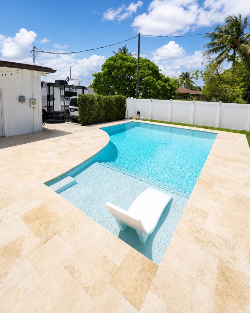 New backyard pool with travertine deck and white fence built by Canet Group