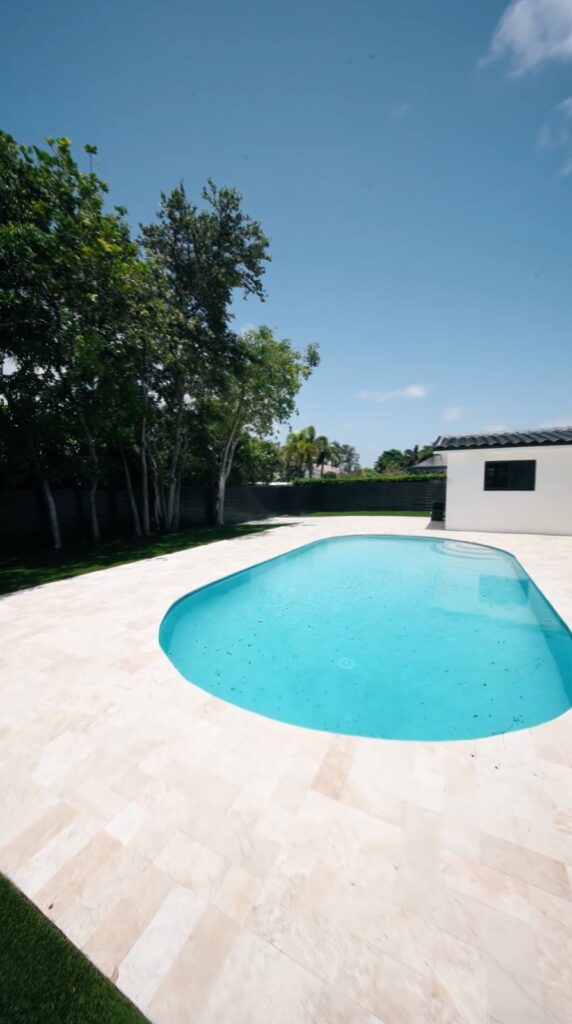 Renovated oval pool in a South Florida backyard by Canet Group