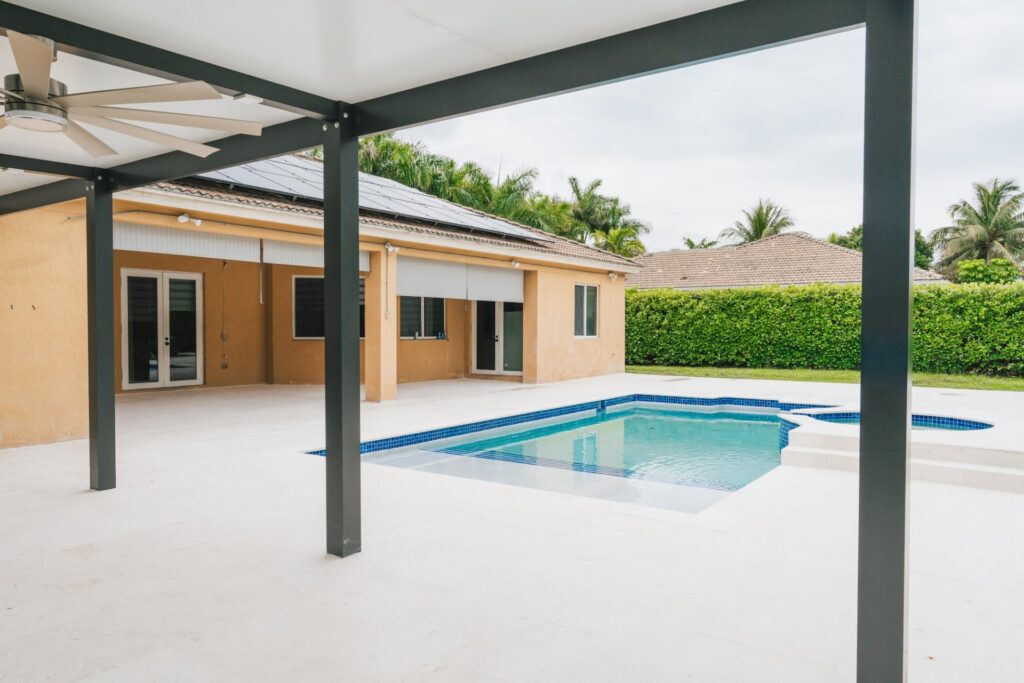Aluminum pergola on a pool deck behind a home, built by Canet Group