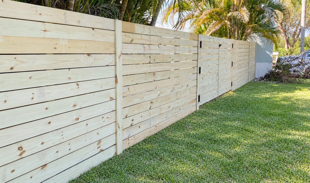 Pine horizontal wood privacy fence along a backyard lawn