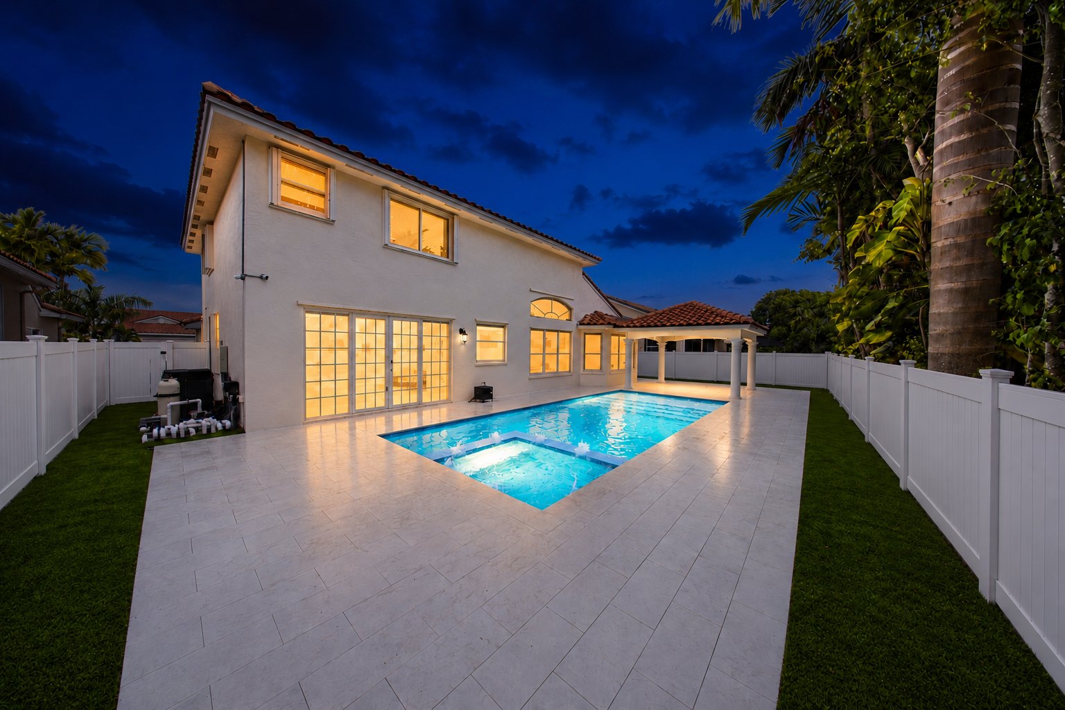 Pool, deck and home lit at twilight, built by Canet Group in South Florida