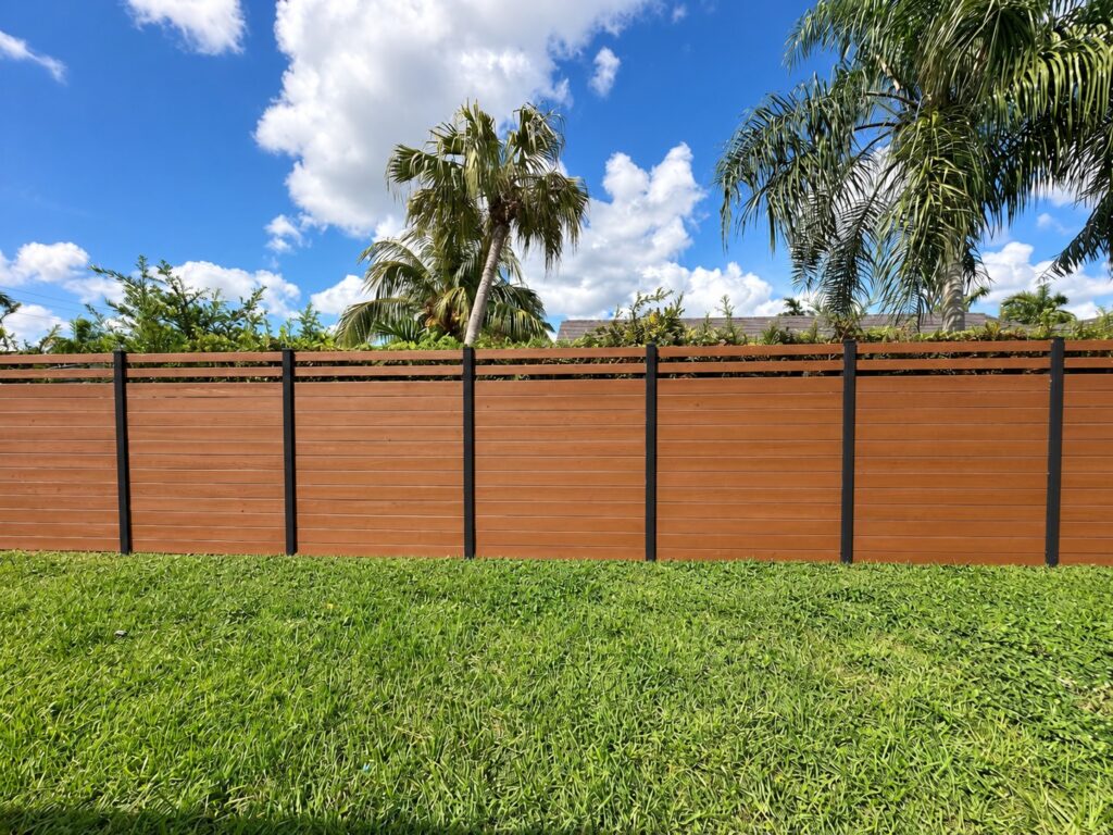 Wood privacy fence with black posts in a backyard with palm trees