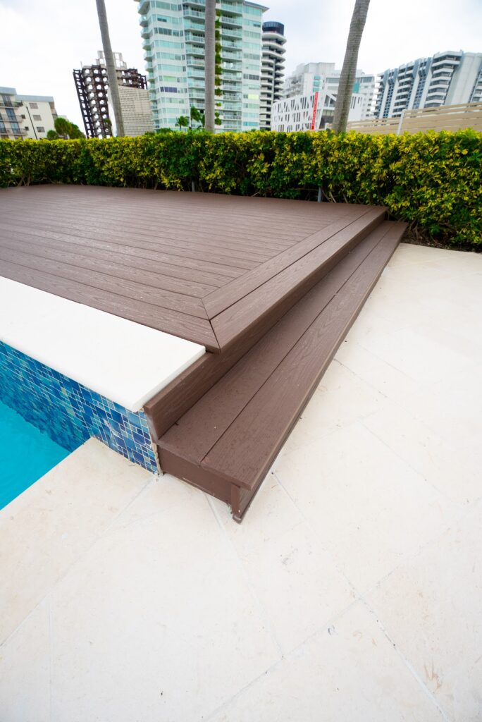 Composite deck boards meeting the pool edge with blue glass tile