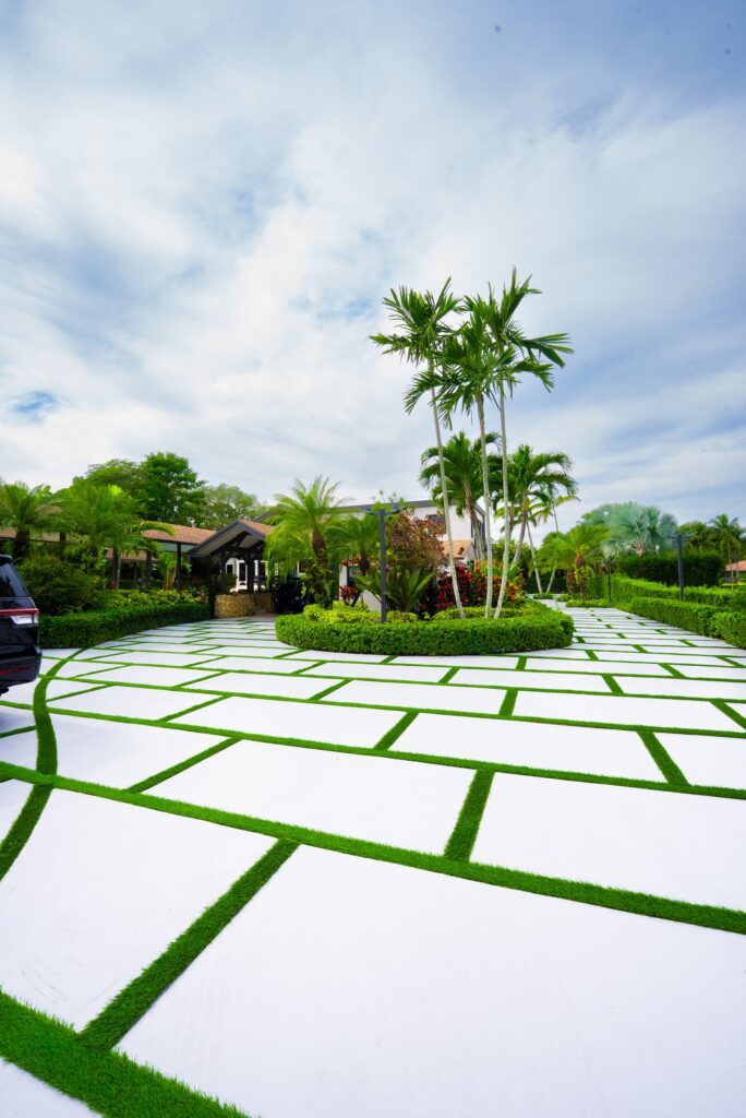 White concrete driveway slabs with artificial turf joints in a South Florida front yard