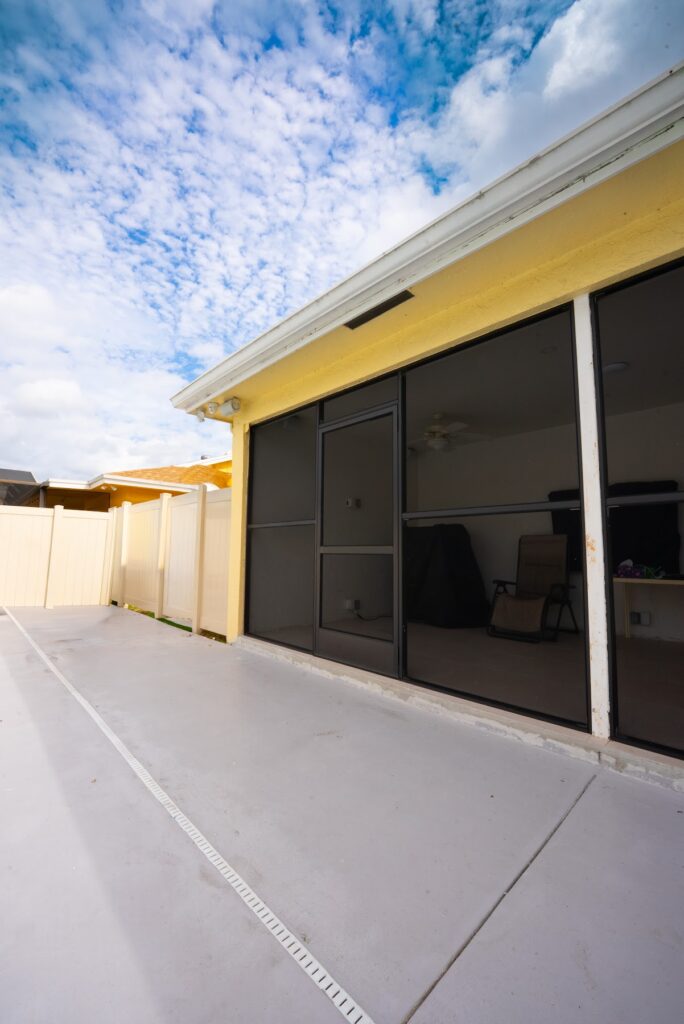New concrete patio beside a screened porch in a South Florida backyard