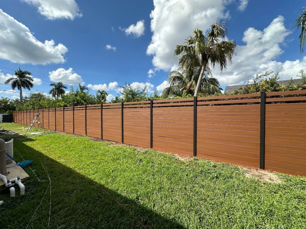 Horizontal wood privacy fence with black posts along a backyard lawn