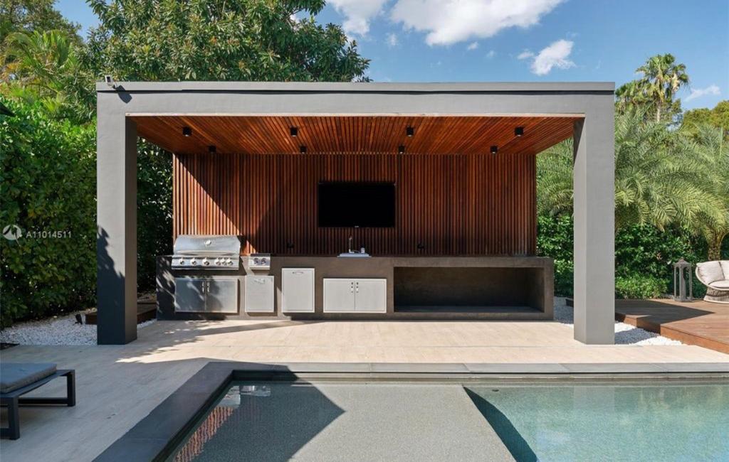 Modern pavilion with wood ceiling and outdoor kitchen beside a pool in South Florida