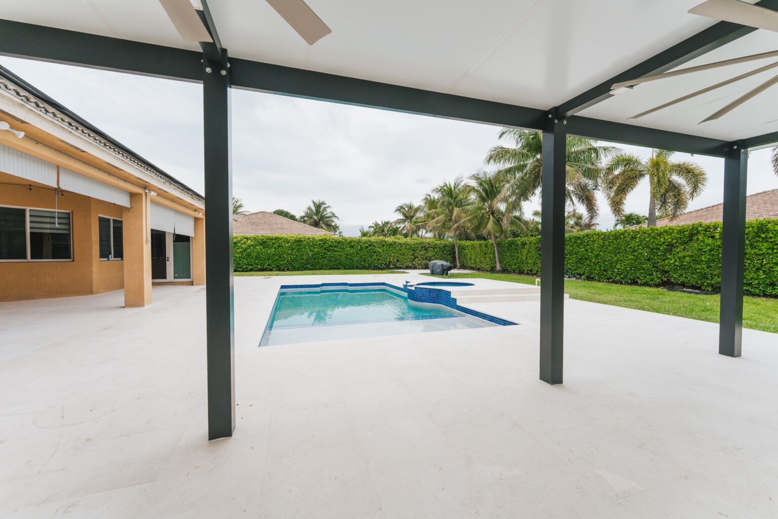 Covered aluminum pergola over a new pool deck in a South Florida backyard