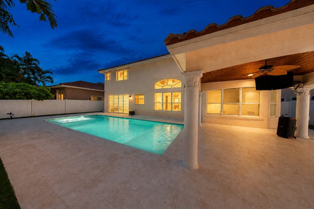 Renovated pool deck and covered patio lit at night