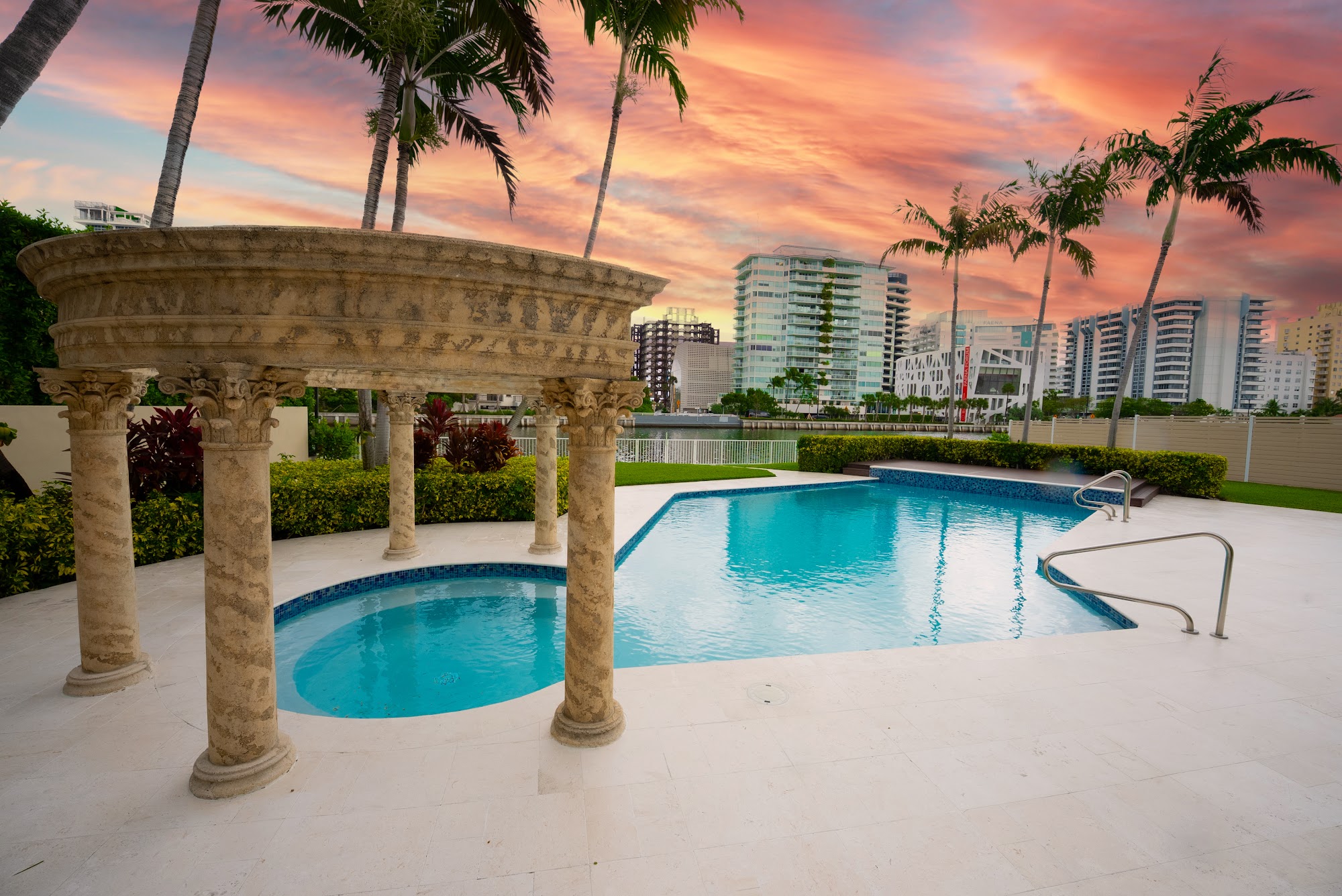 Pool with a stone column gazebo and lounge deck at sunset in South Florida