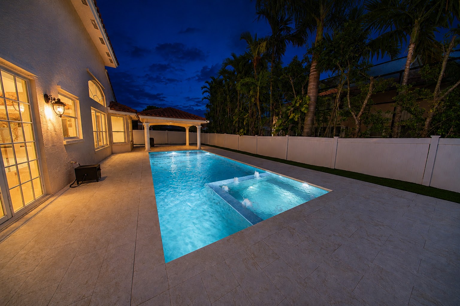 Renovated pool and raised spa with LED lighting at night, South Florida