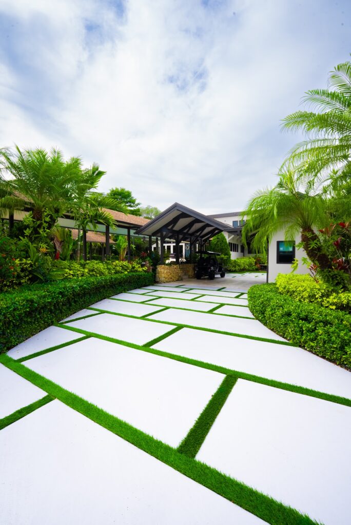 White concrete driveway with turf joints around a landscaped palm island