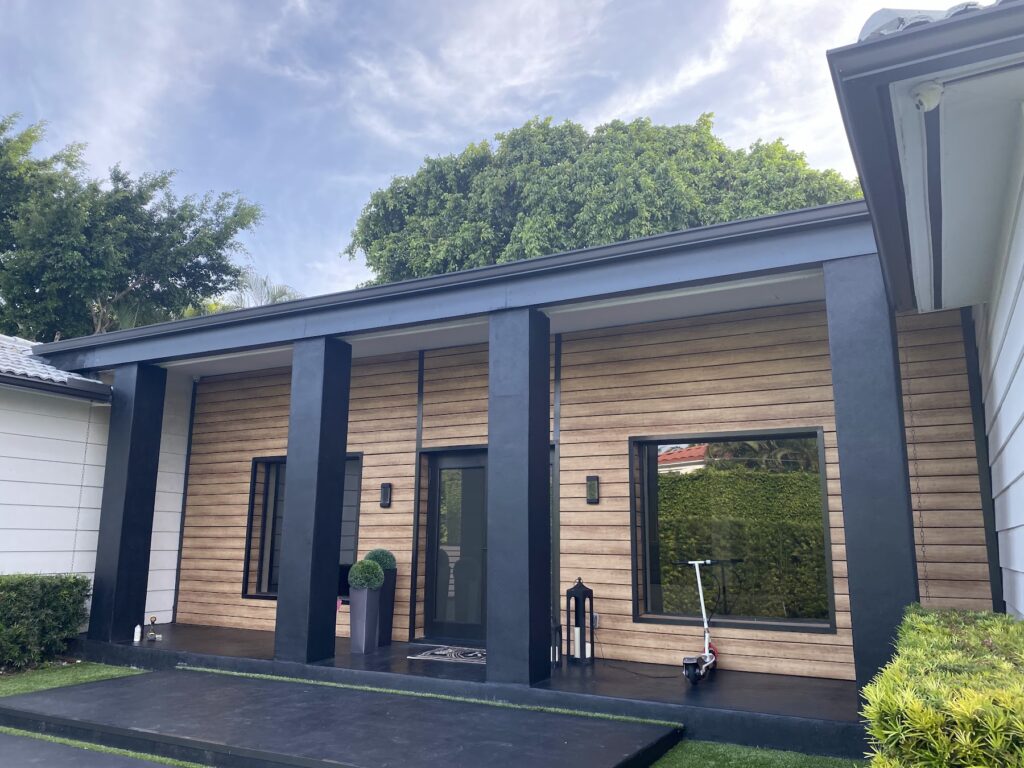Wood-look slat cladding with black columns on a modern home entry